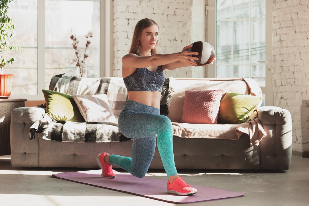 Young woman teaching at home online courses of fitness, aerobic, sporty lifestyle while being quarantine